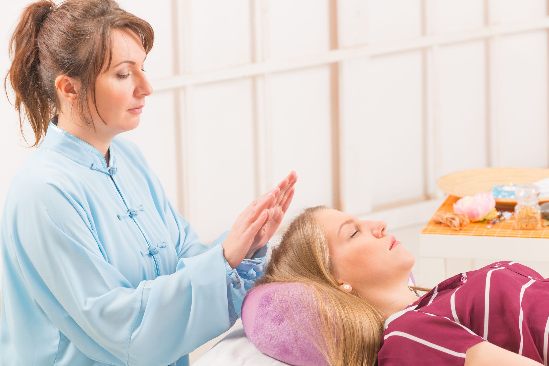 Professional Reiki healer doing reiki treatment to young woman