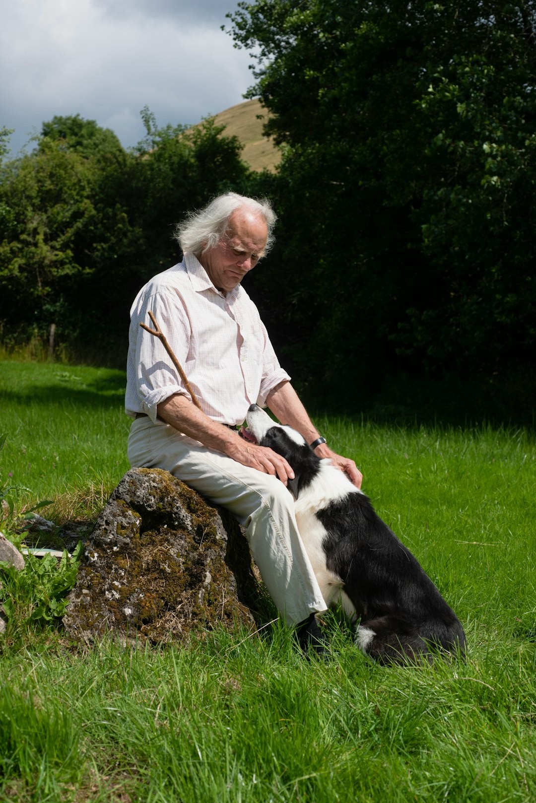 a man sitting on a rock with a dog